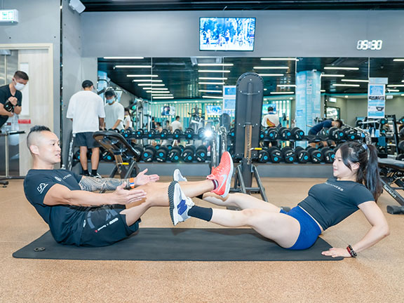 Partner v-sit circle: sit on the ground facing each other, with the upper body leaning slightly back and hands resting on the ground. Lift both feet off the ground and draw circles – first clockwise, then anticlockwise – to exercise your abdominal muscles.