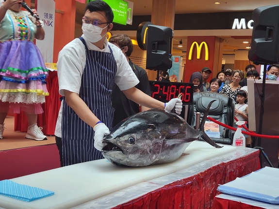The chef wows the crowd with his prowess in tuna-slicing.