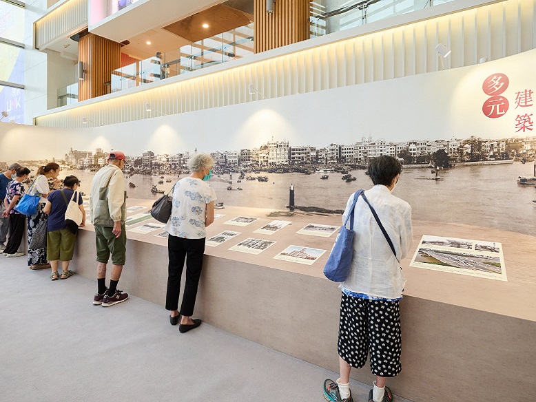 Elderly visitors carefully examine the historical photographs.