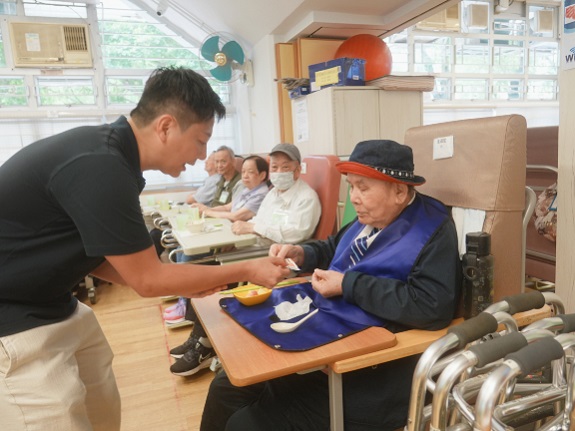 Tai Po District Councillor Lee Man-kit distributes soft meal vouchers to seniors at the day care centre.