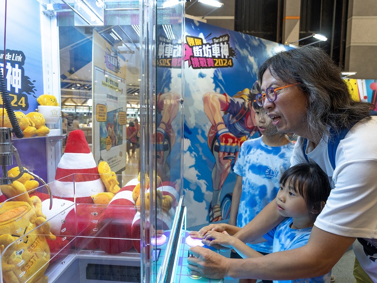 Parents and children enjoy a fun break together at the claw machine after completing the Family Category competition.