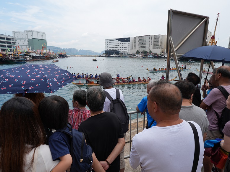 一眾街坊在岸邊觀賽，為龍舟隊伍加油鼓勁。