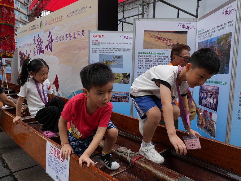 Children experience being dragon boat racers on the 60-foot-long dragon boat on display.