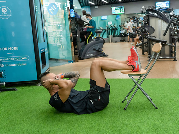 Place both feet on a chair and do crunches to exercise abdominal muscles.