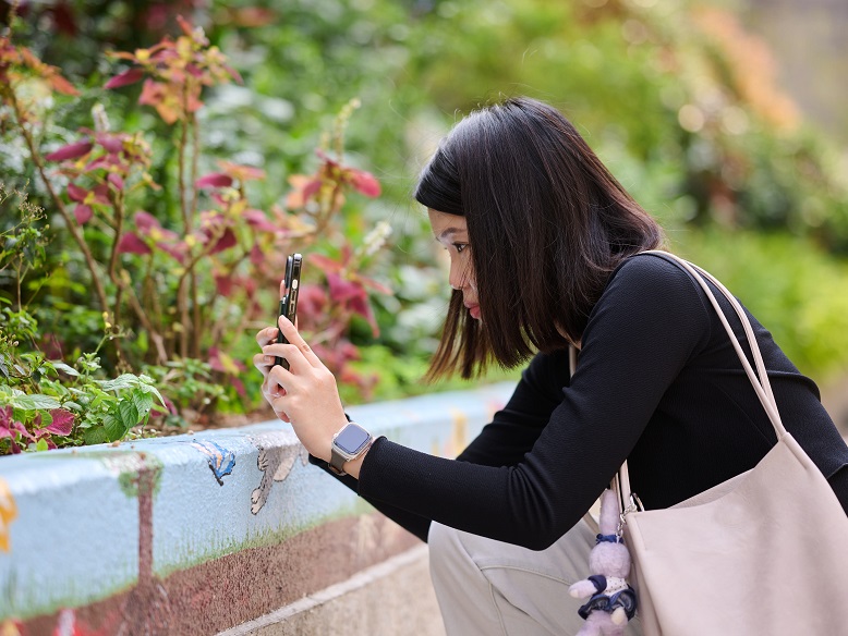 A visitor takes photos of butterflies with her smartphone.