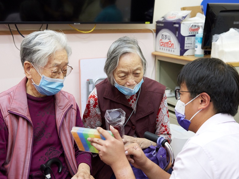 Representatives distributing gifts, such as thermos bottles, to the residents of the elderly home.