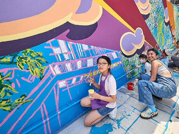 Artist DD Yung (right) guides participants in mural creation.