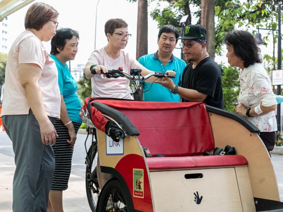 CWAS trainer, Gavin (second from right), showing volunteers how the locking mechanism on the trishaw works. 