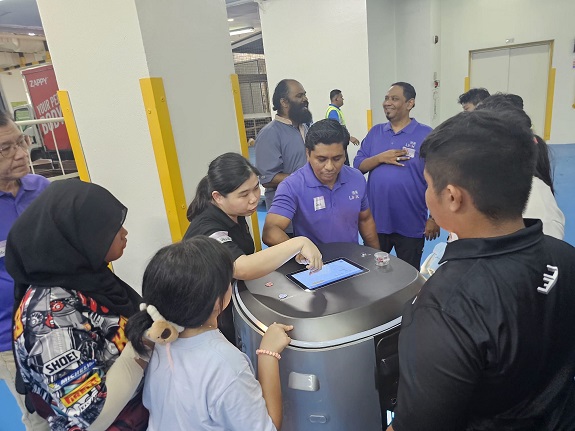 Jurong Point team showing the participants how the settings on the cleaning robot work. 
