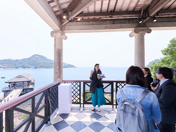 Marisa Yiu introduces the exhibition from Murray House’s elegant balcony, framed by sweeping views of Stanley’s picturesque waterfront.