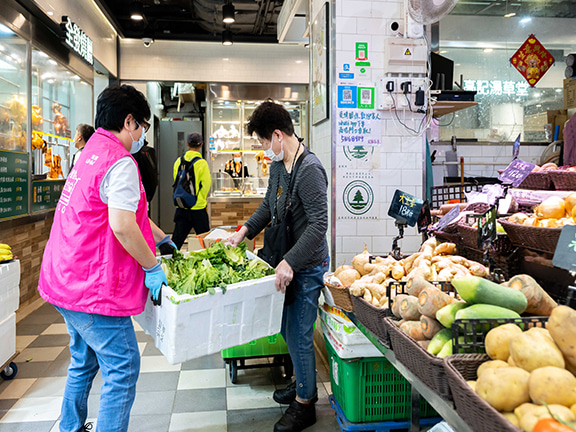 The grocers helped put the boxes of vegetable onto Chun’s trolley.