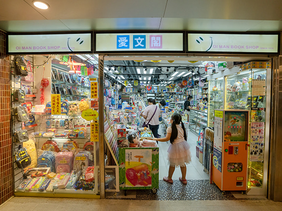 At Oi Man Bookshop, plush toys are lined up on a storefront display, catching the eye of children walking by.