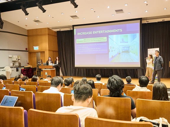 Fuchsia and her Russian and Japanese teammates present their shopping centre improvement proposal to the judging panel. 